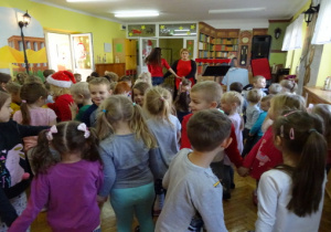 Dzieci i prowadzące koncert tańczą w parach.